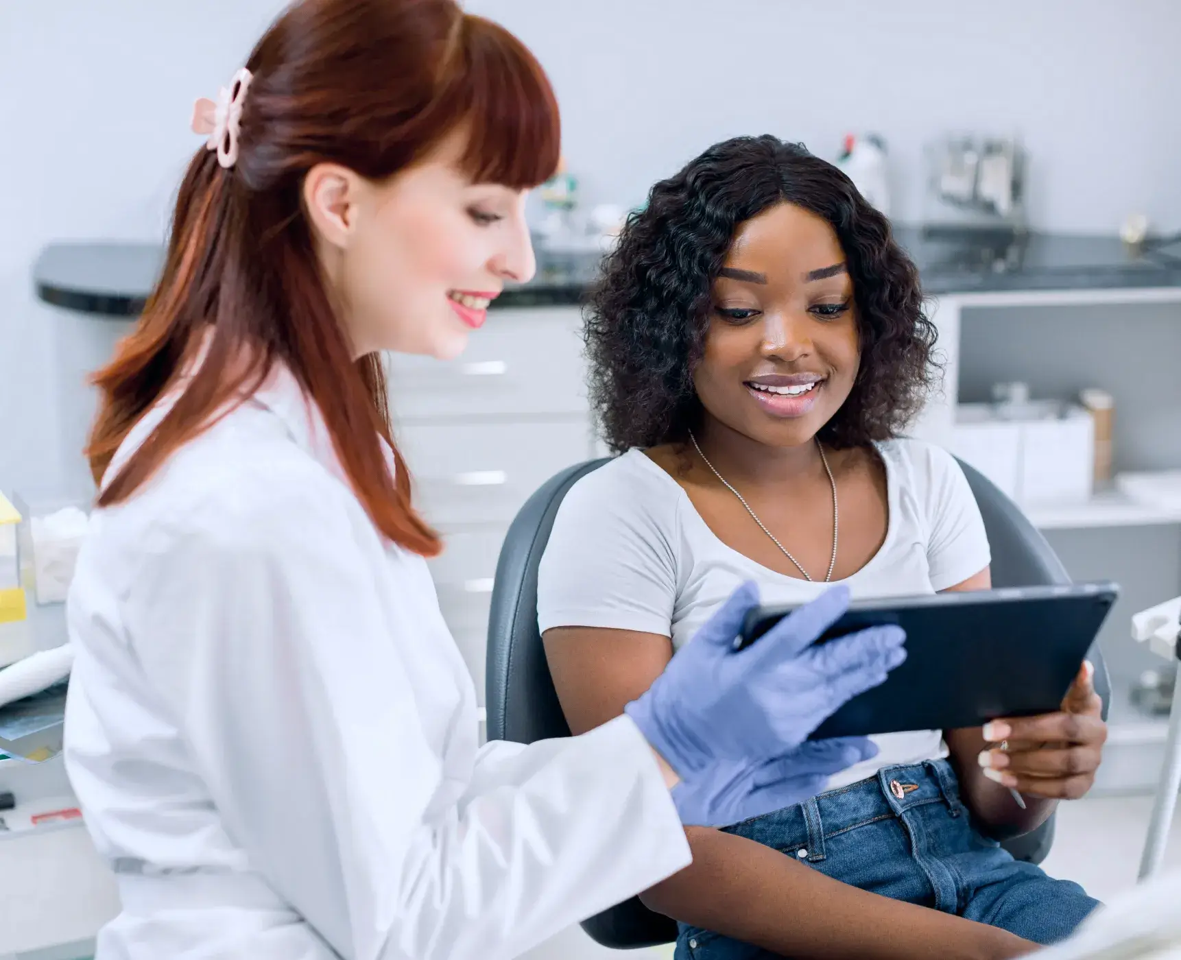 A photo of a dentist showing a tablet to a smiling patient in a dental office.